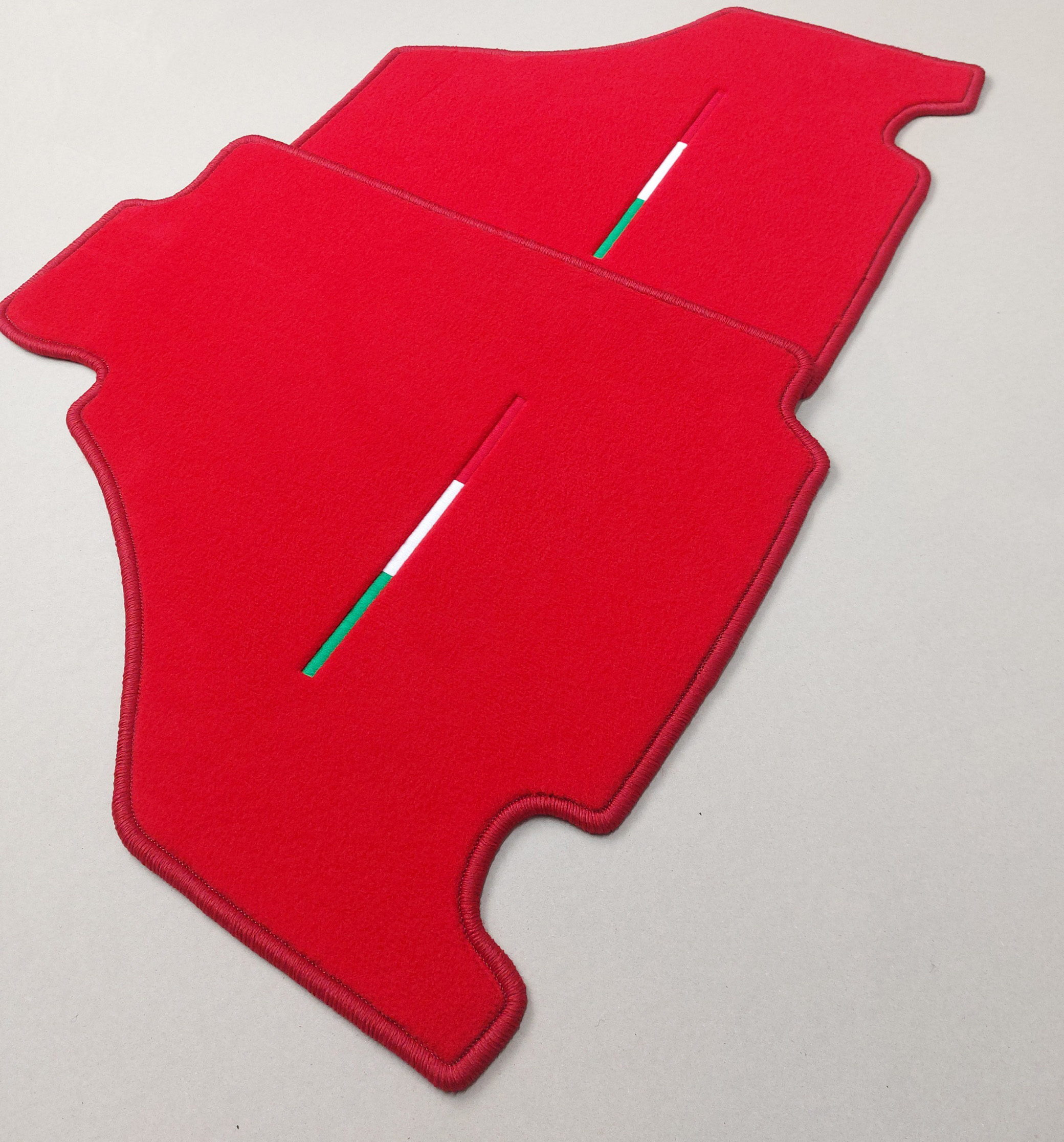 Rote Fussmatten seitlich Ferrari Stick Tricolore Zwei Fussmatten fuer einen Ferrari in rot mit Tricolore Stick seitliche ansicht.